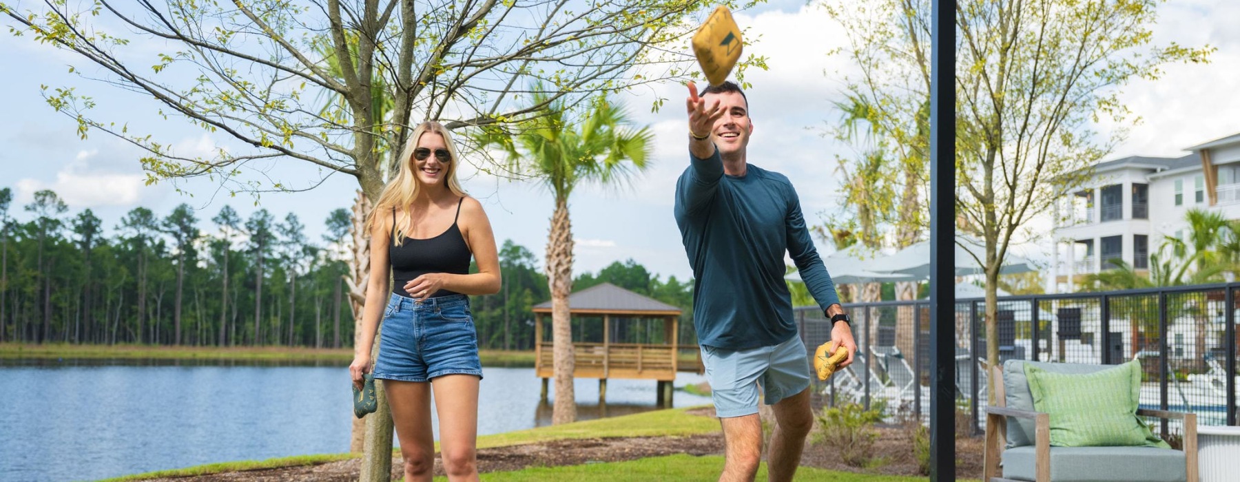 Couple playing cornhole outdoors at Marion Lake new apartments in Savannah, GA.